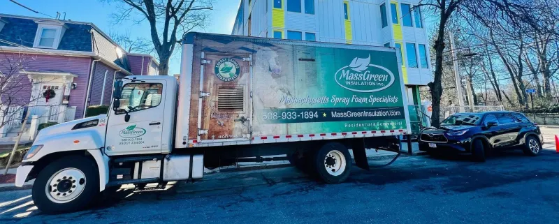 Mass Green Insulation box truck parked outside a new apartment building